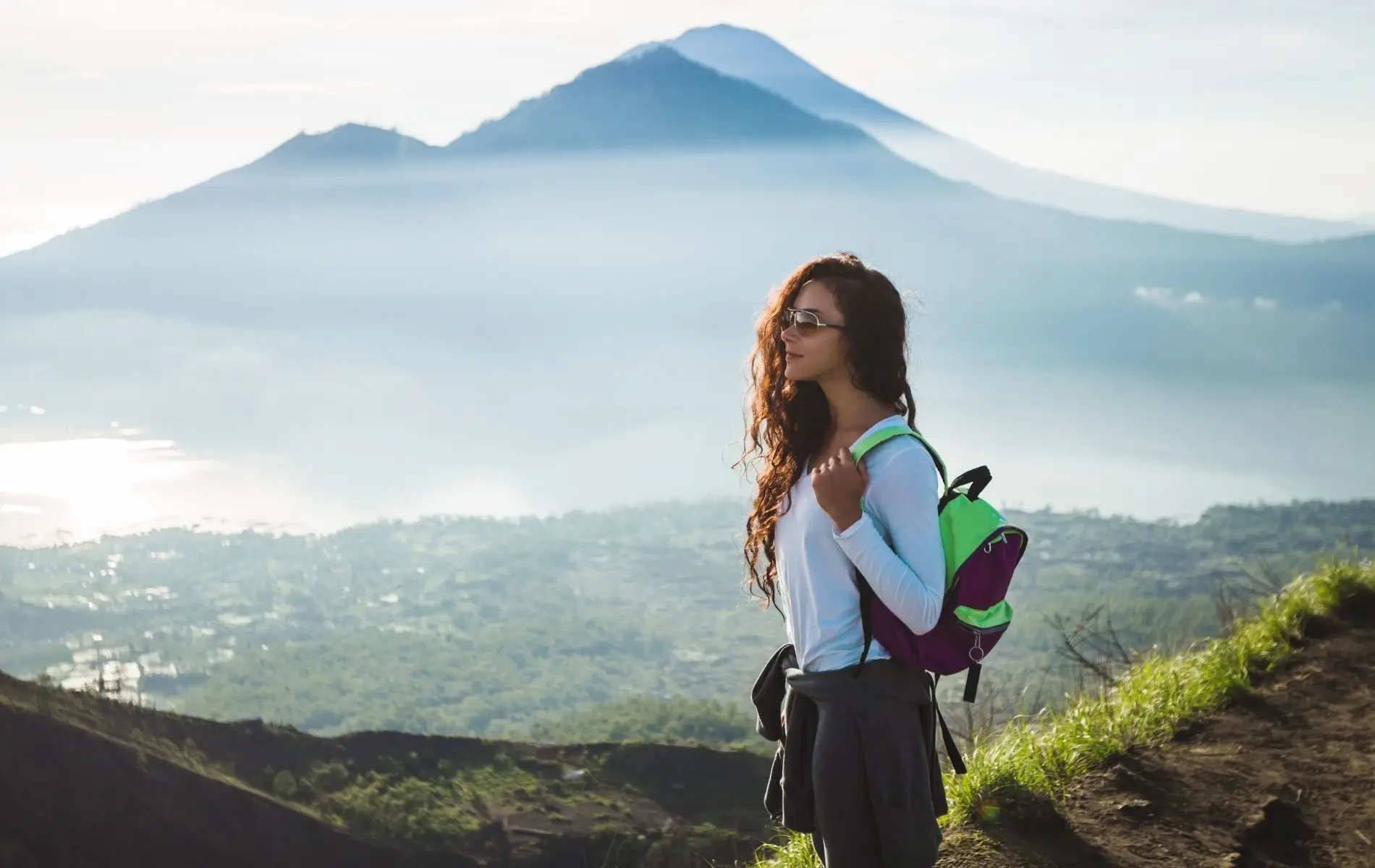 A hiker taking in the sunrise view above the clouds at Mt. Batur